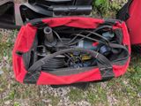 un sac rouge contenant des outils, posé par terre
