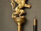 a gold lion on top of a pole next to a pencil