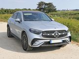the mercedes suv is parked on a dirt road in front of a field