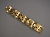 gros plan d'un bracelet en or sur une surface grise