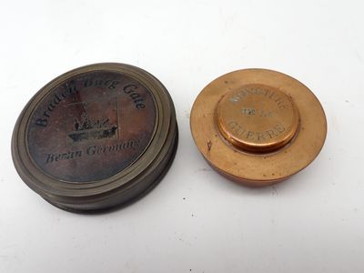 une vieille plaque en laiton et une autre vieille plaque en laiton posées sur une surface blanche