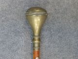 a small metal object with a wooden handle on a gray surface