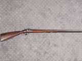 un vieux fusil au canon en bois posé sur un drap à pois