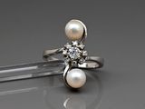 une photo d'une bague ornée de perles et de diamants posée sur une table