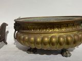 a small statue of a dog standing next to a large brass bowl