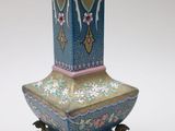 a vase that is sitting on a stand on a white surface