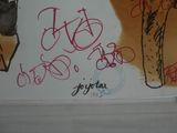 graffiti on the wall of a bathroom with a toilet and a trash can