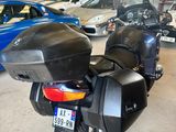 une moto noire garée dans un garage à côté d'autres voitures