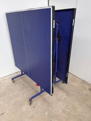 a blue ping pong table in the middle of a room