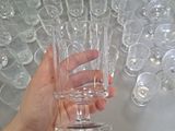 a person holding a glass in front of a table full of empty glasses