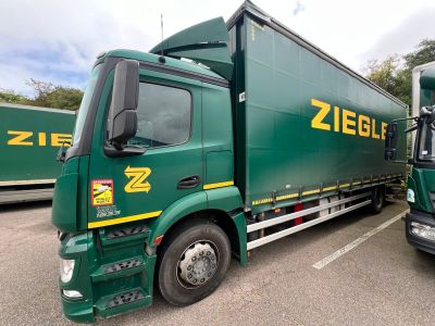two green semi trucks parked in a parking lot