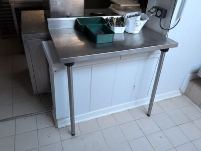 a kitchen with a stainless steel table and a green bin