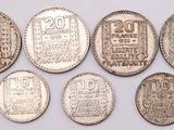 six silver coins of different sizes and shapes on a white surface