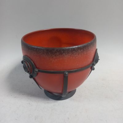 un bol rouge et noir posé sur une table blanche