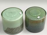 two green jars with lids on a white surface