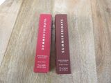 two red boxes of lipstick on a wooden table with a white background