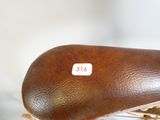 une selle en cuir marron sur un vélo, sur laquelle est collé un autocollant