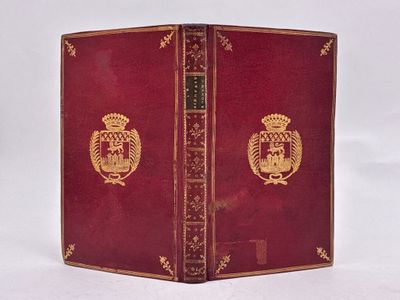un vieux livre à la couverture rouge ornée d'un emblème doré