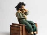 a doll sitting on a wooden box with a cell phone in her hand