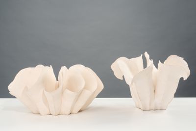 deux vases blancs posés sur une table, sur fond gris