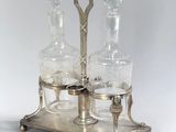 two glass decanters on a metal stand with a silver base