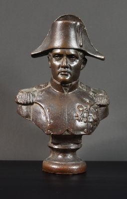 buste en bronze d'un homme coiffé d'un chapeau, posé sur une table noire
