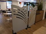 un paravent au milieu d'une pièce où se trouvent des tables et des chaises