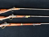 three old guns are lined up on a black surface