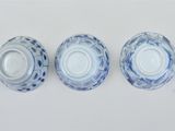four blue and white plates are lined up on a white surface