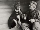 photo en noir et blanc d'un homme assis à côté d'un chien