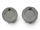 pair of small plates with red flowers on them sitting on a white surface