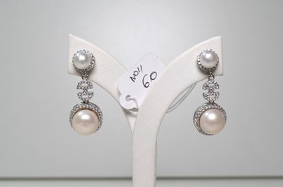 une paire de boucles d'oreilles en perles et diamants exposée dans une bijouterie