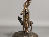 bronze statue of a woman with a dog on a rock