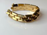 gros plan d'un bracelet en or sur une surface blanche