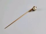 a close up of a gold pin with a pearl on it