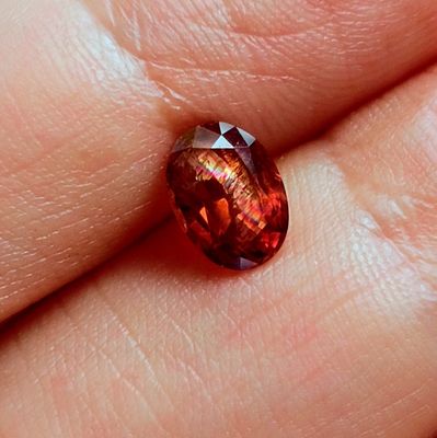 quelqu'un tient un diamant rouge à la main, à un doigt