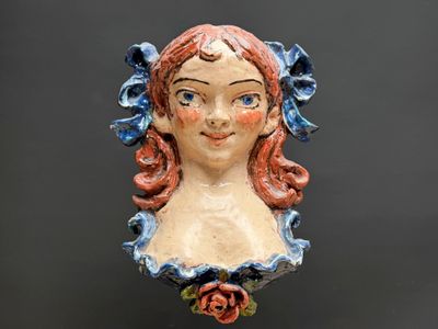 une tête de femme en céramique, avec une rose dans les cheveux