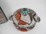 a brown and green pot sitting on a table next to a cookie tin
