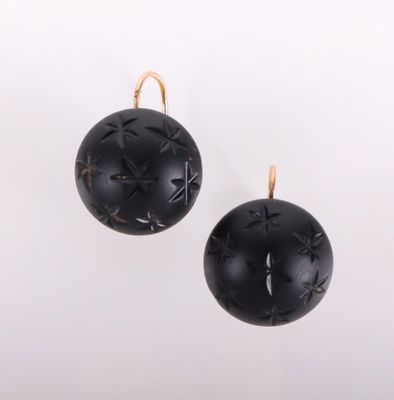 une paire de boucles d'oreilles noires et dorées sur fond blanc