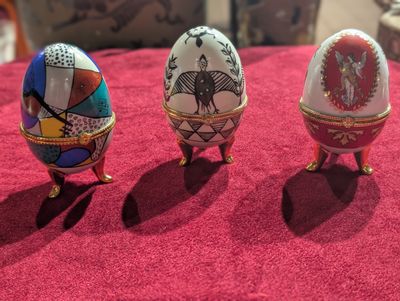 trois œufs décorés posés sur une nappe rouge
