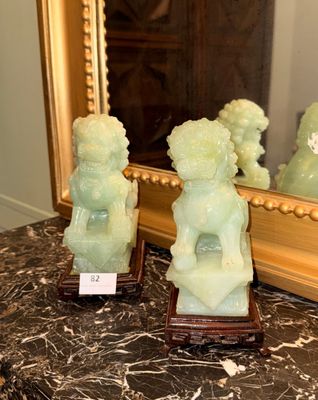 two jade statues sitting on a table in front of a mirror