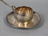an antique silver plate with a spoon and saucer on top of it