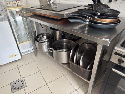 pots and pans sit on a stainless steel counter in a commercial kitchen