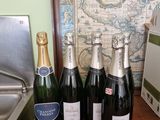 Plusieurs bouteilles de champagne sont alignées sur une table, à côté d'une carte
