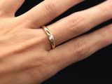 La femme porte à son doigt une bague en or sertie d'un diamant.