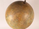 a large globe that is on a stand on a white surface