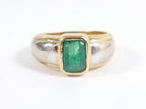 a close up of a gold ring with a green stone