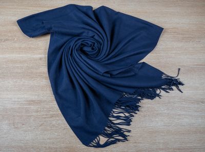 a blue scarf with fringes laying on a wooden floor
