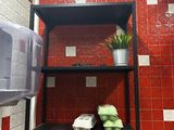 a red tiled bathroom with a black shelf and a potted plant