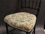 une chaise noire sur laquelle est posé un coussin d'assise à motifs floraux